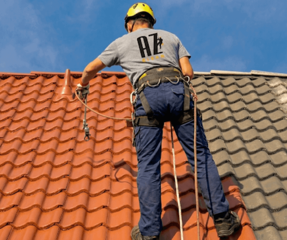 Pracownik az clean zabezpieczony linami wykonujący czyszczenie dachu z dachówki ceramicznej